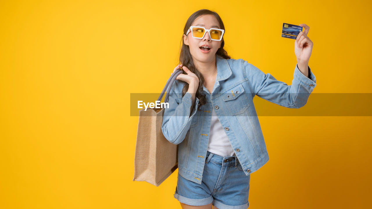 PORTRAIT OF SMILING YOUNG WOMAN WEARING SUNGLASSES