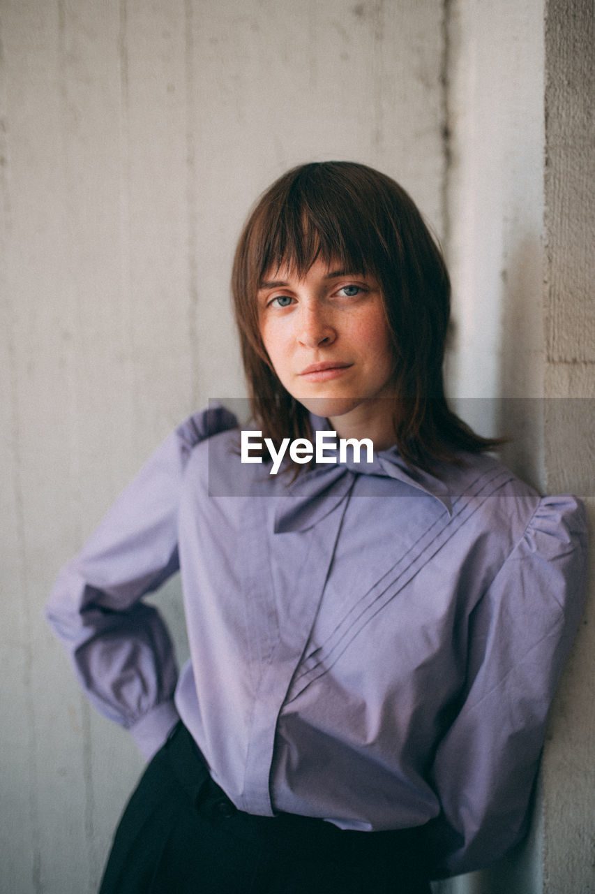 Portrait of woman standing against wall