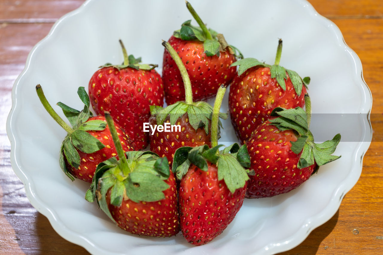 CLOSE-UP OF STRAWBERRIES IN PLATE ON TABLE