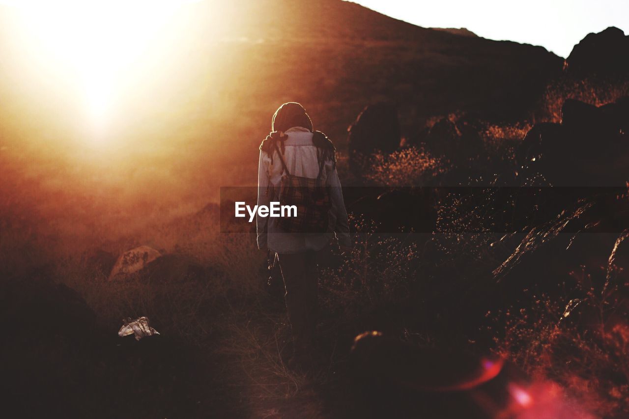 Rear view of woman walking on mountain during sunset