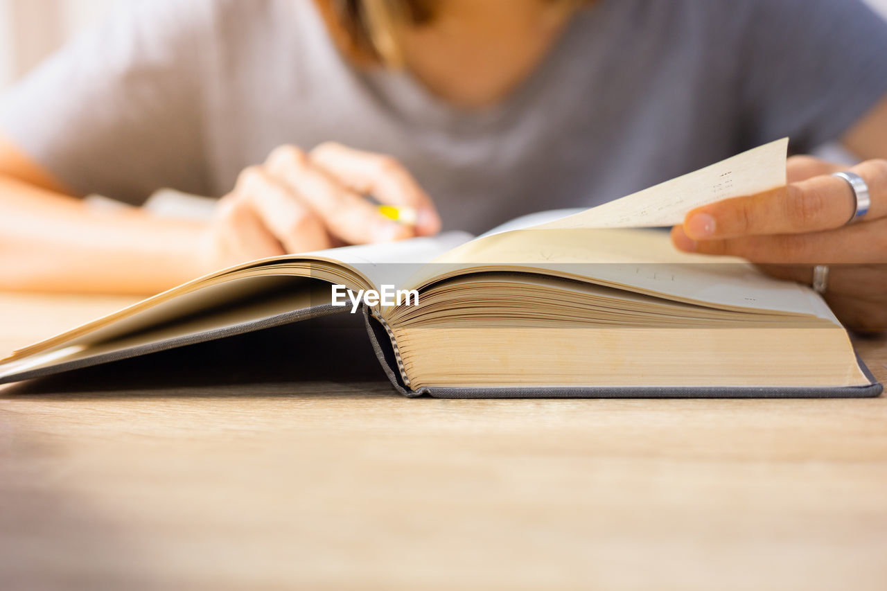 Close up and selective focus shot of woman who is reading textbook on table shows education concept 