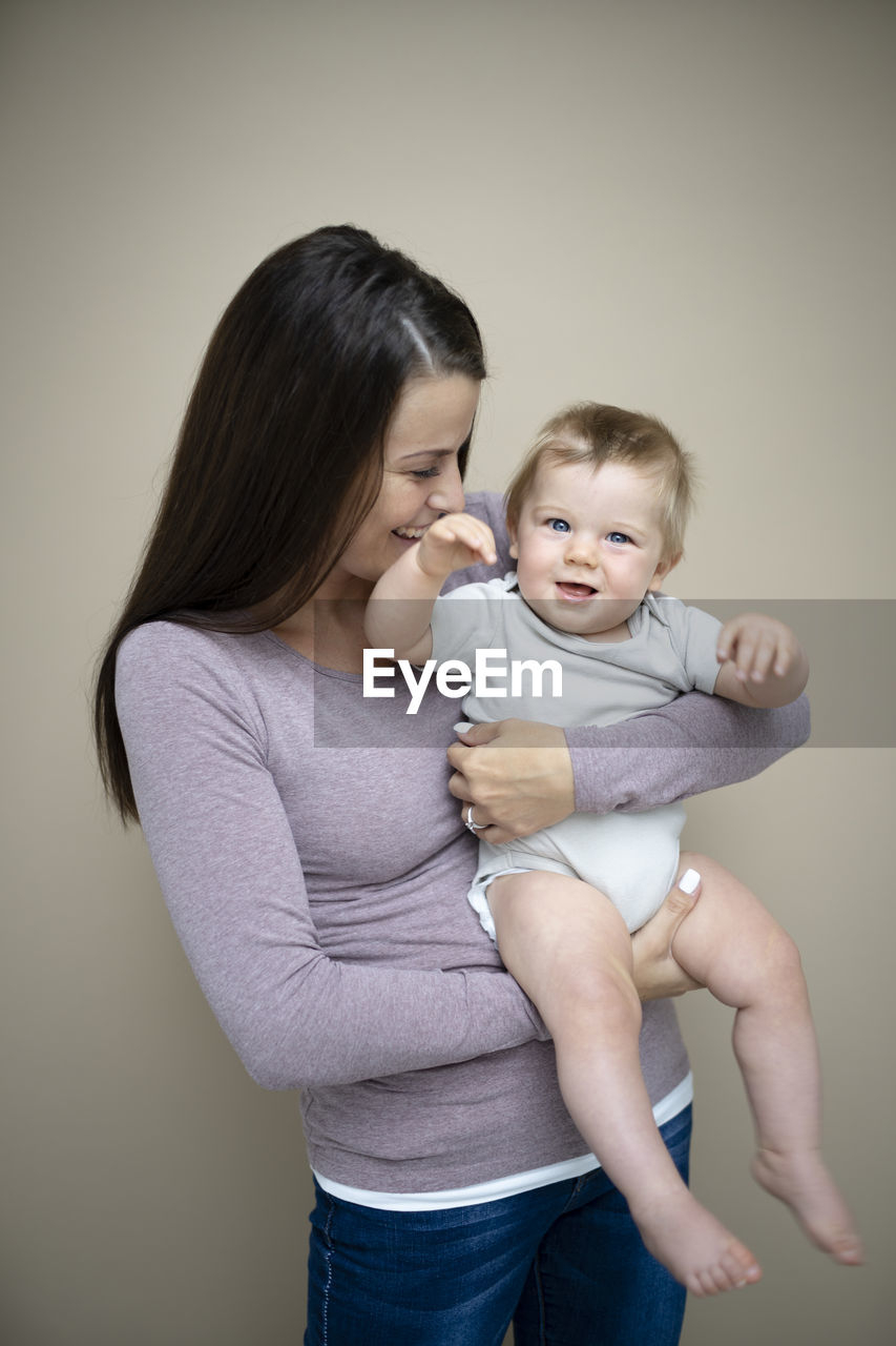 side view of mother carrying daughter at home