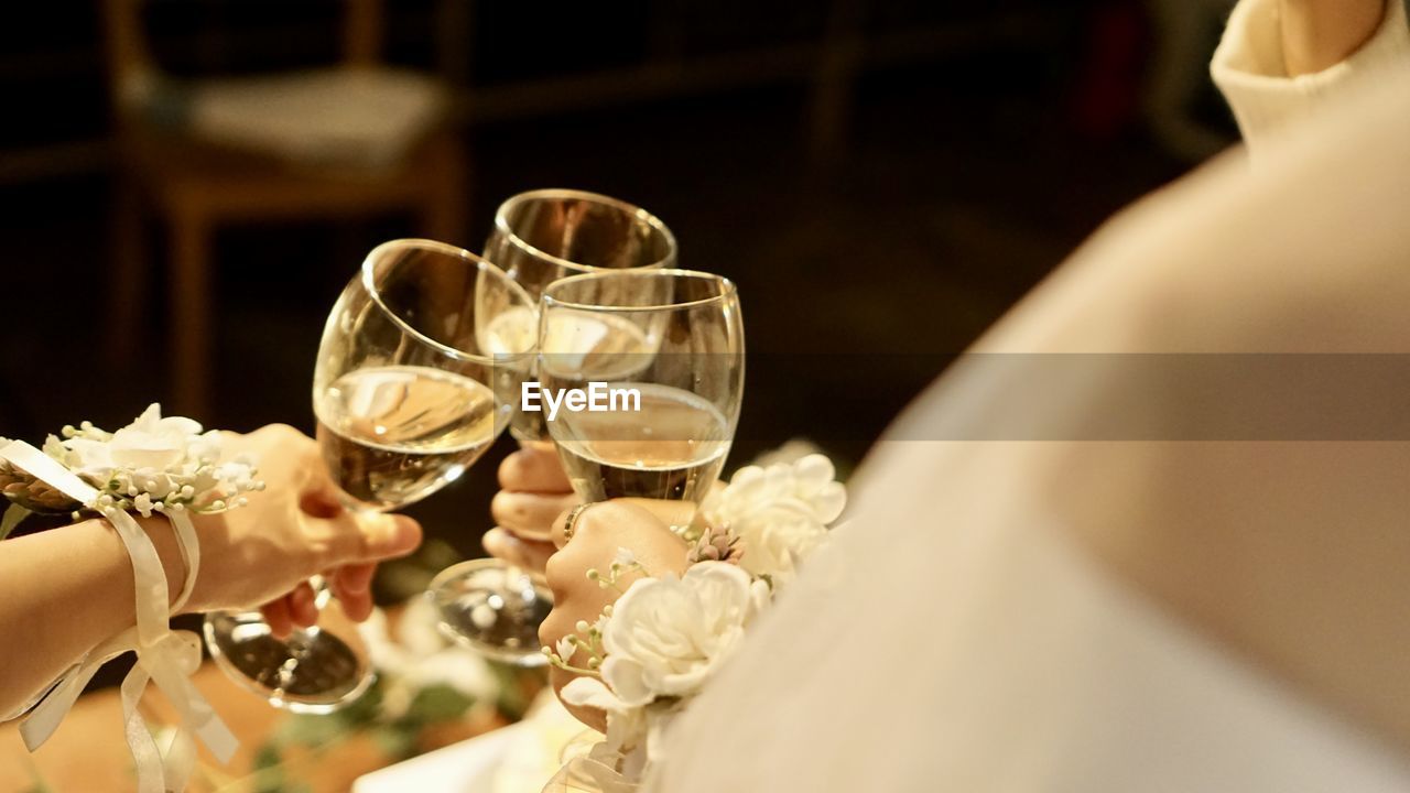 midsection of bride and groom holding wineglass