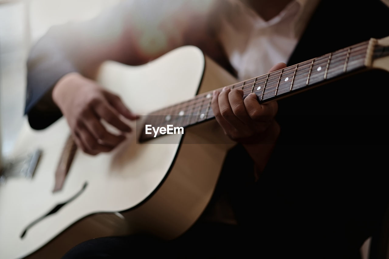 Midsection of man playing guitar