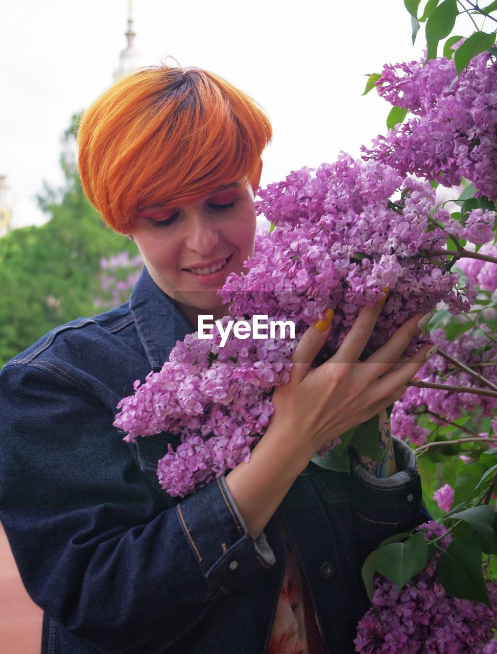 Portrait of smiling woman standing against purple flowering plants