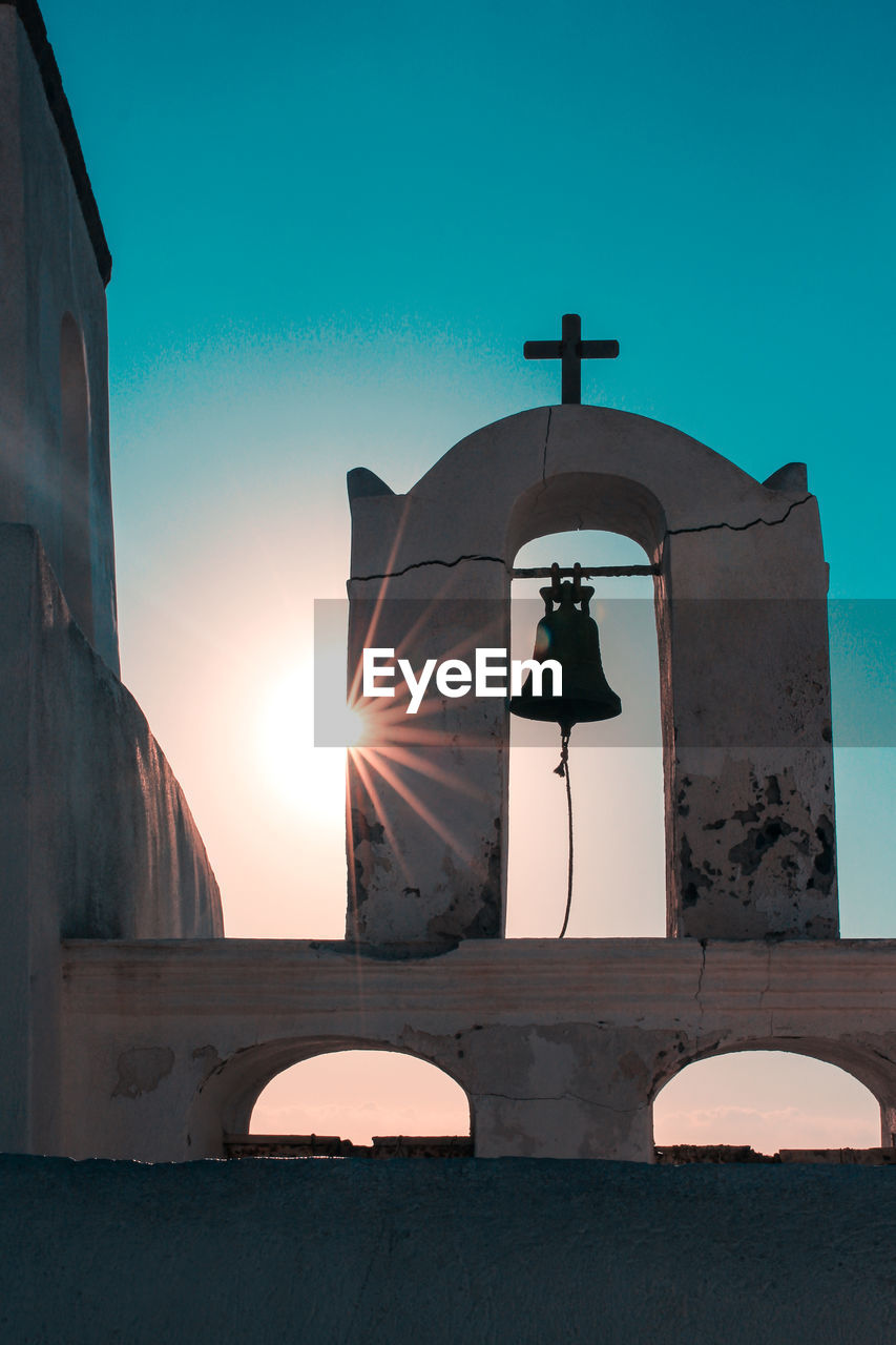 Rear view of chirch bell against building against clear blue sky