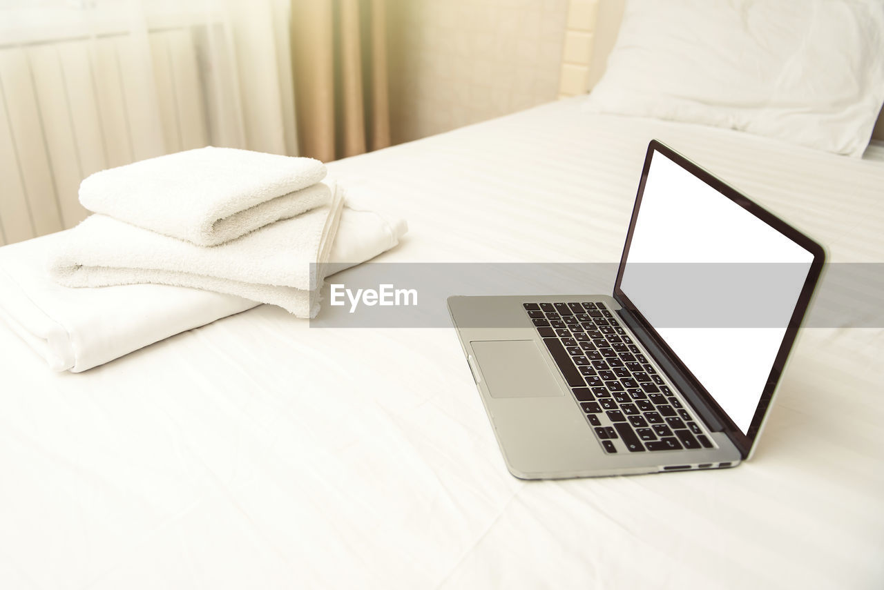LOW ANGLE VIEW OF LAPTOP ON BED