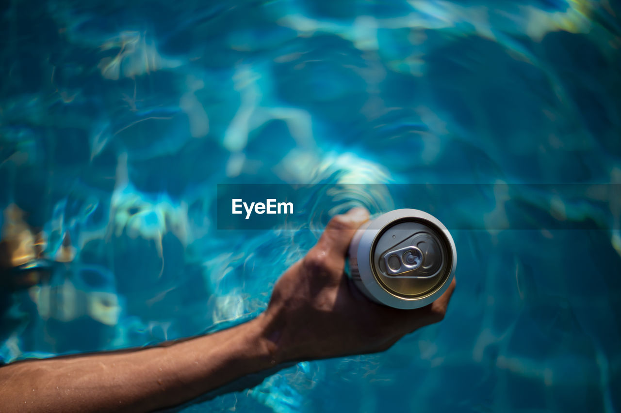 Selective focus white beer can in hand. man is soaking in the pool with an open beer can relax 