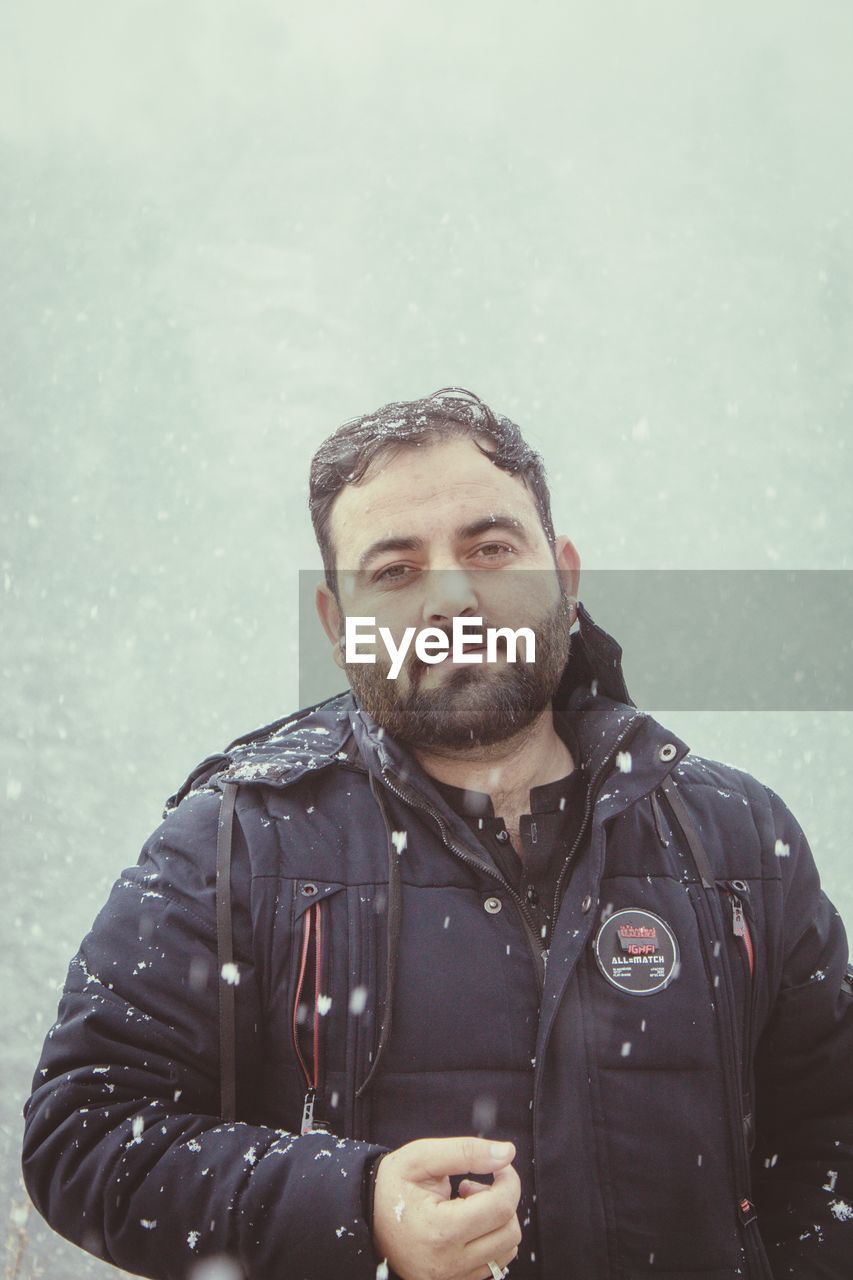 one person, winter, beard, adult, clothing, cold temperature, men, jacket, facial hair, warm clothing, waist up, snow, portrait, nature, person, front view, young adult, copy space, snowing, standing, looking, wet, serious, rain, lifestyles, coat, stubble, looking at camera, leisure activity, water, day, outdoors, protection, human face