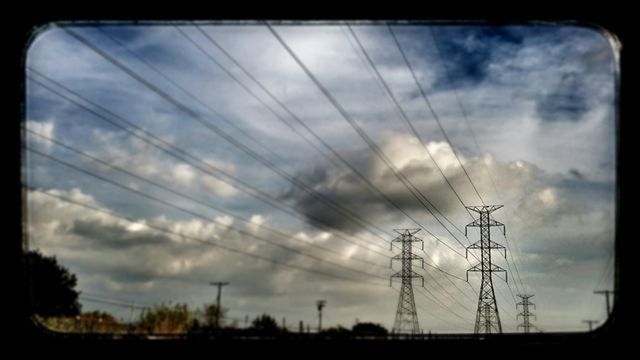 LOW ANGLE VIEW OF ELECTRICITY PYLONS AGAINST CLOUDY SKY