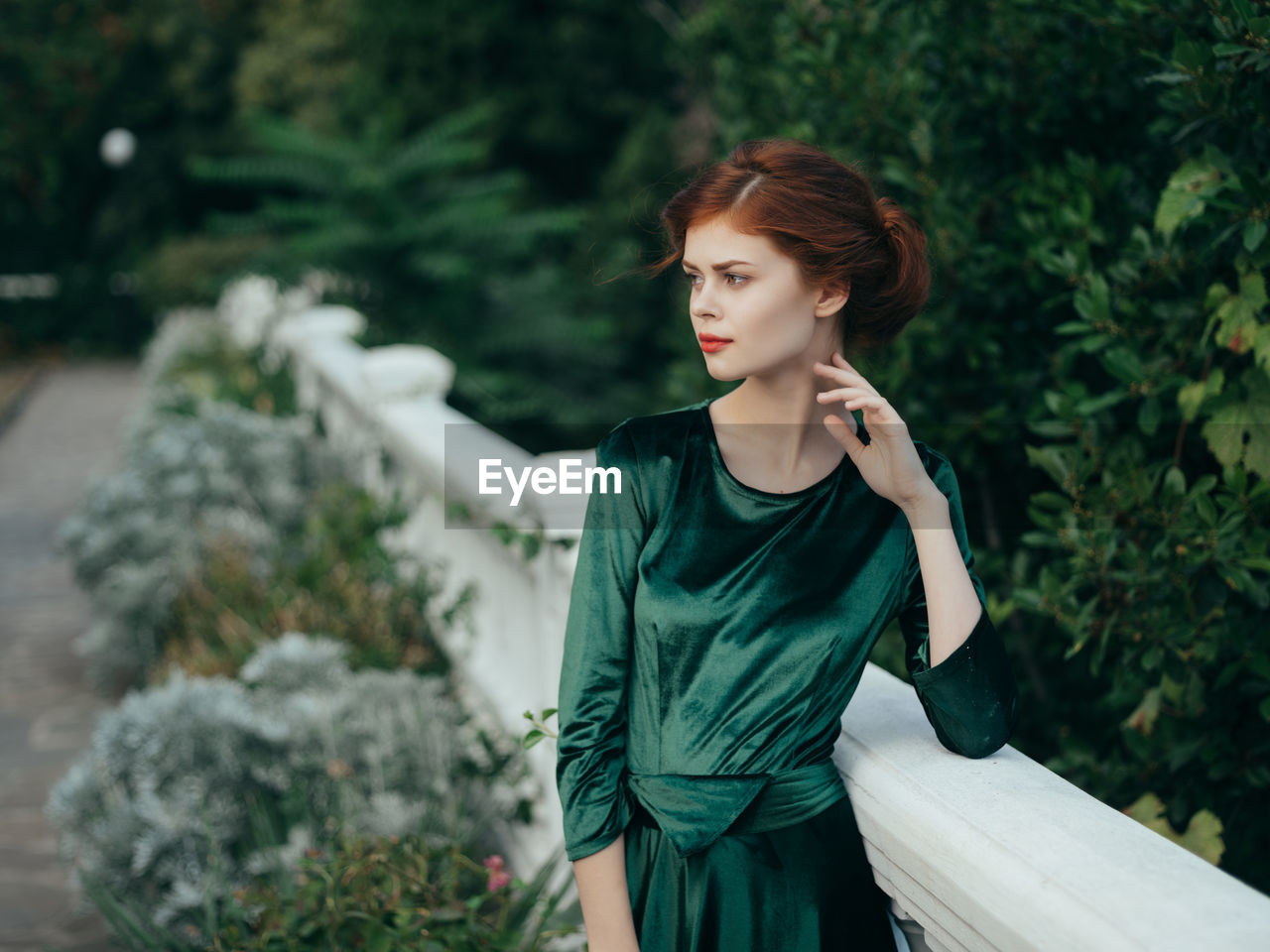 Young woman looking away while standing against plants