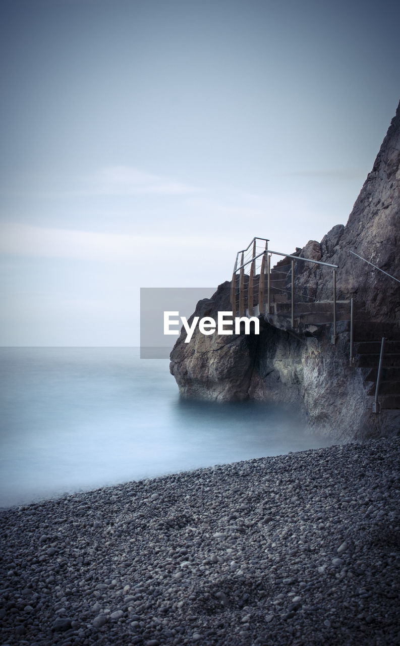 View of staircase on cliffs at coast against sky