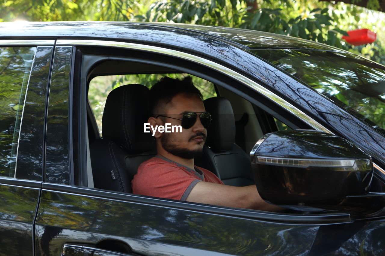 Young man in sunglasses sitting in car