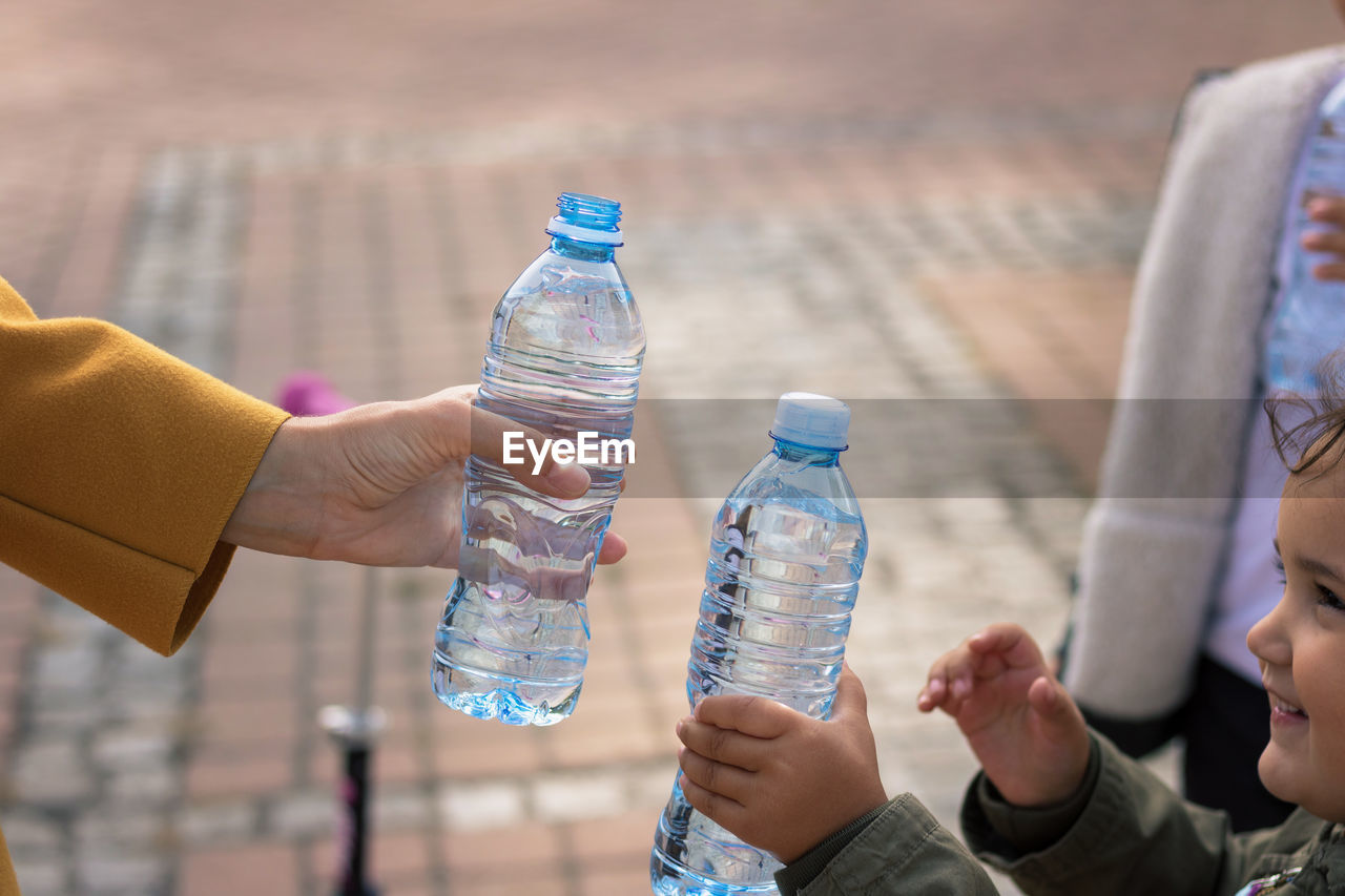 Mother and daughter holding water bottles in city