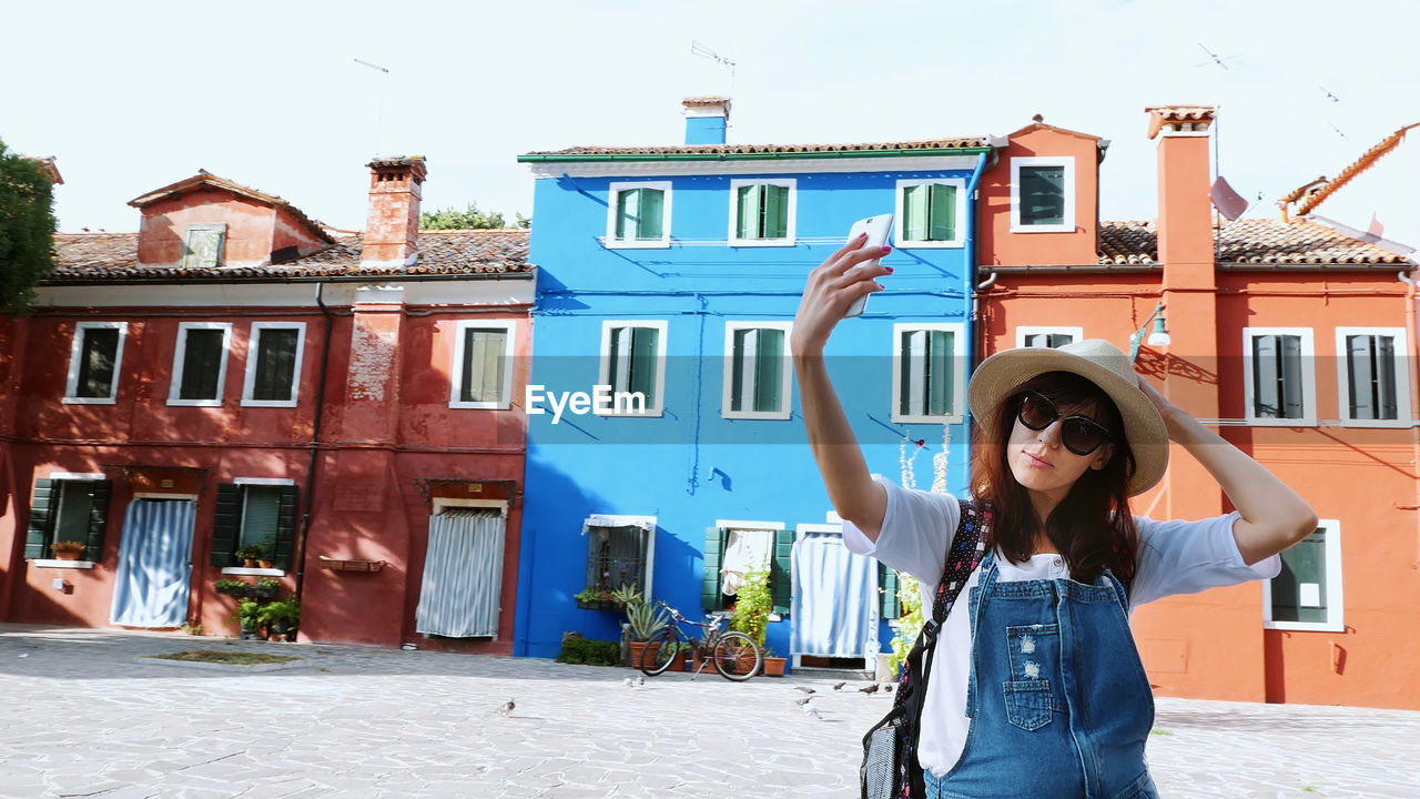Burano island with multicolor houses near venice. tourist, young woman, girl in sun glasses, hat
