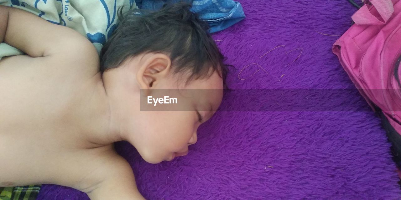 HIGH ANGLE VIEW OF CUTE BABY SLEEPING ON BED