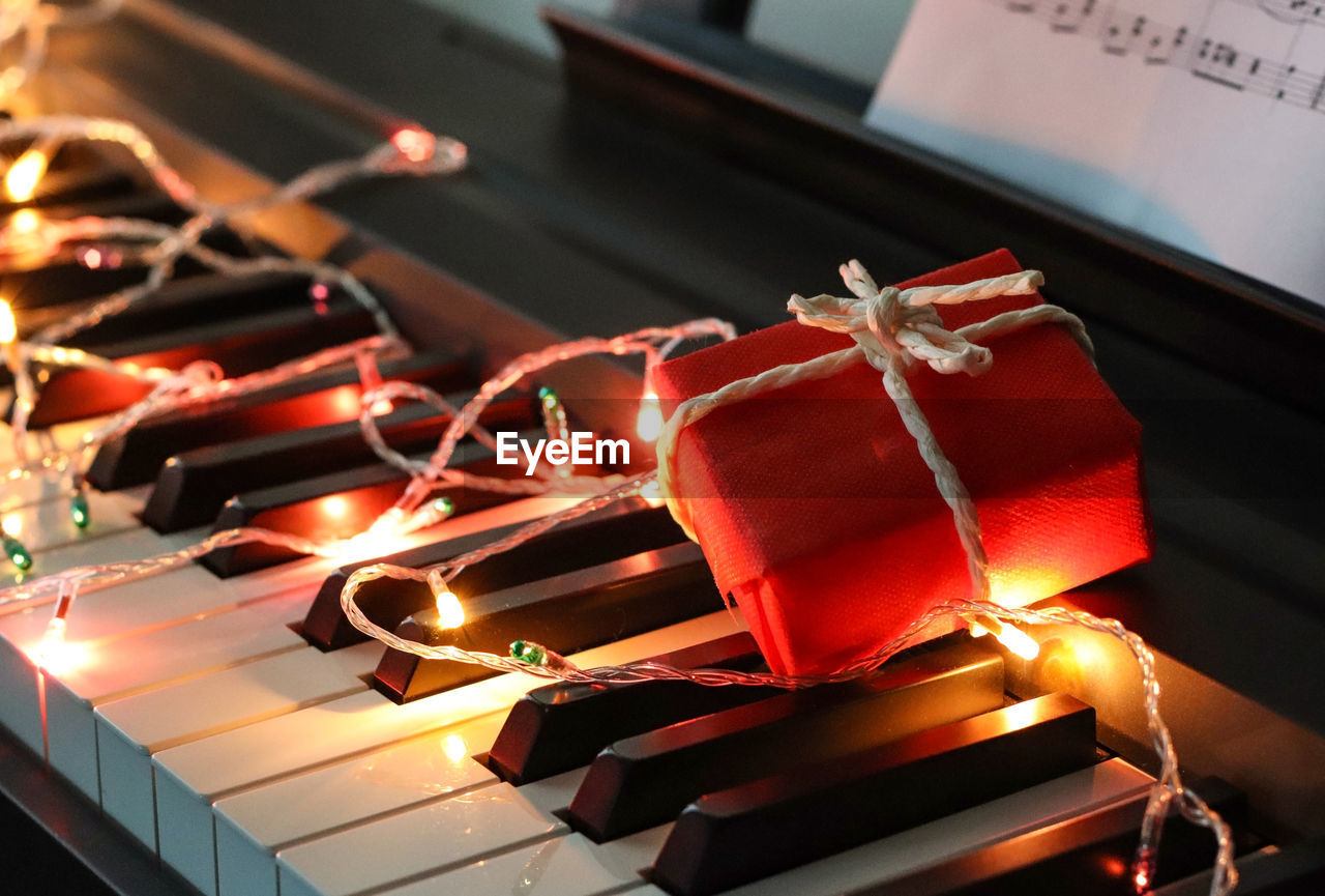 Illuminated christmas lights and gift box on piano