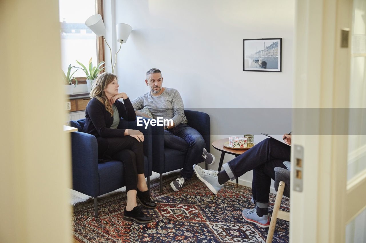 Man and woman talking to counselor while sitting at workshop