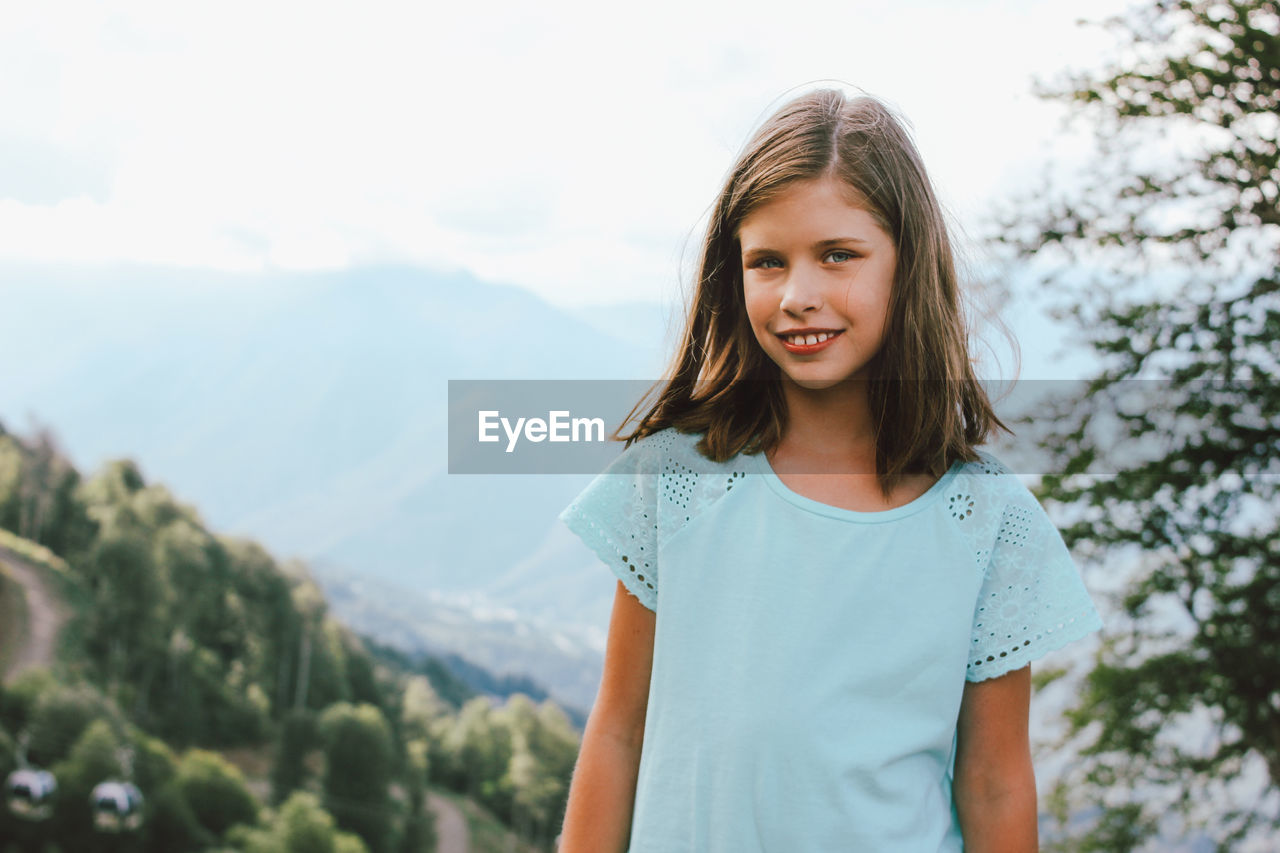 Portrait of smiling girl standing against mountains