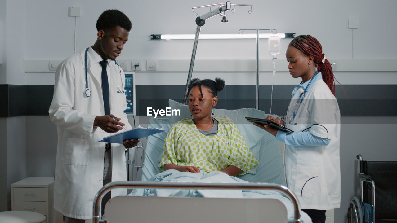 Doctors discussing with patient in ward at hospital