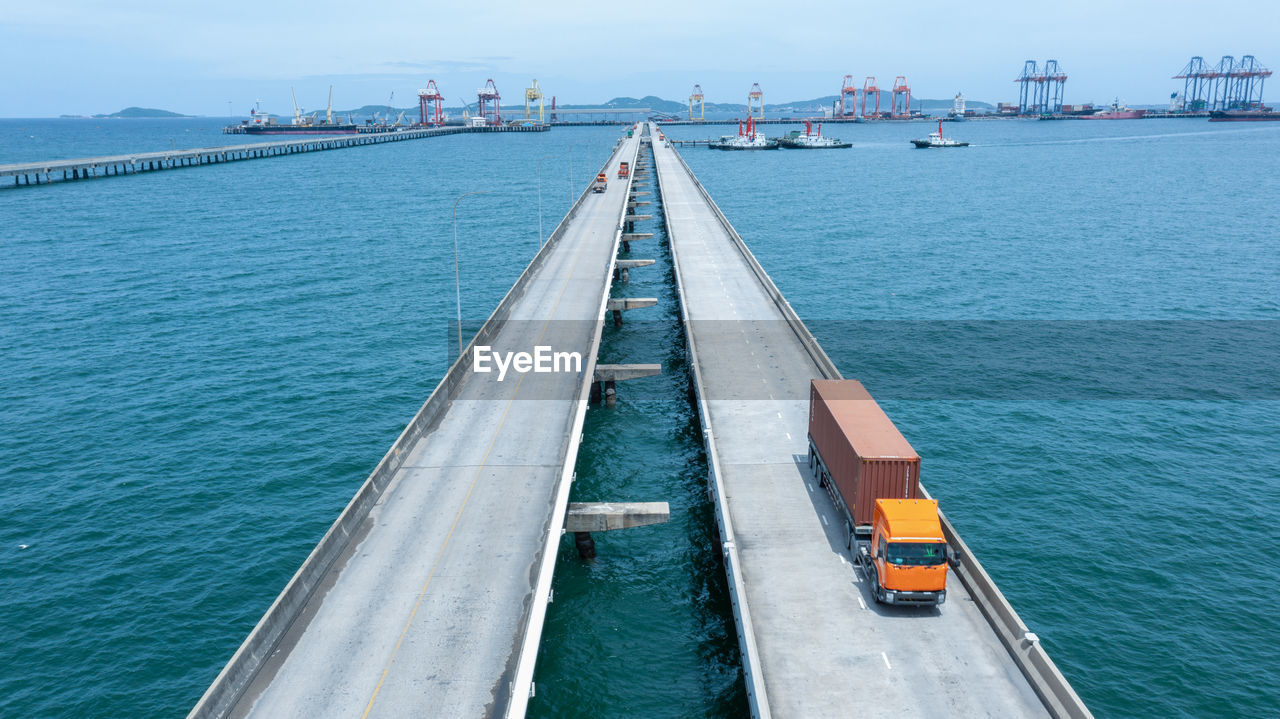 HIGH ANGLE VIEW OF BRIDGE AND SEA AGAINST SKY