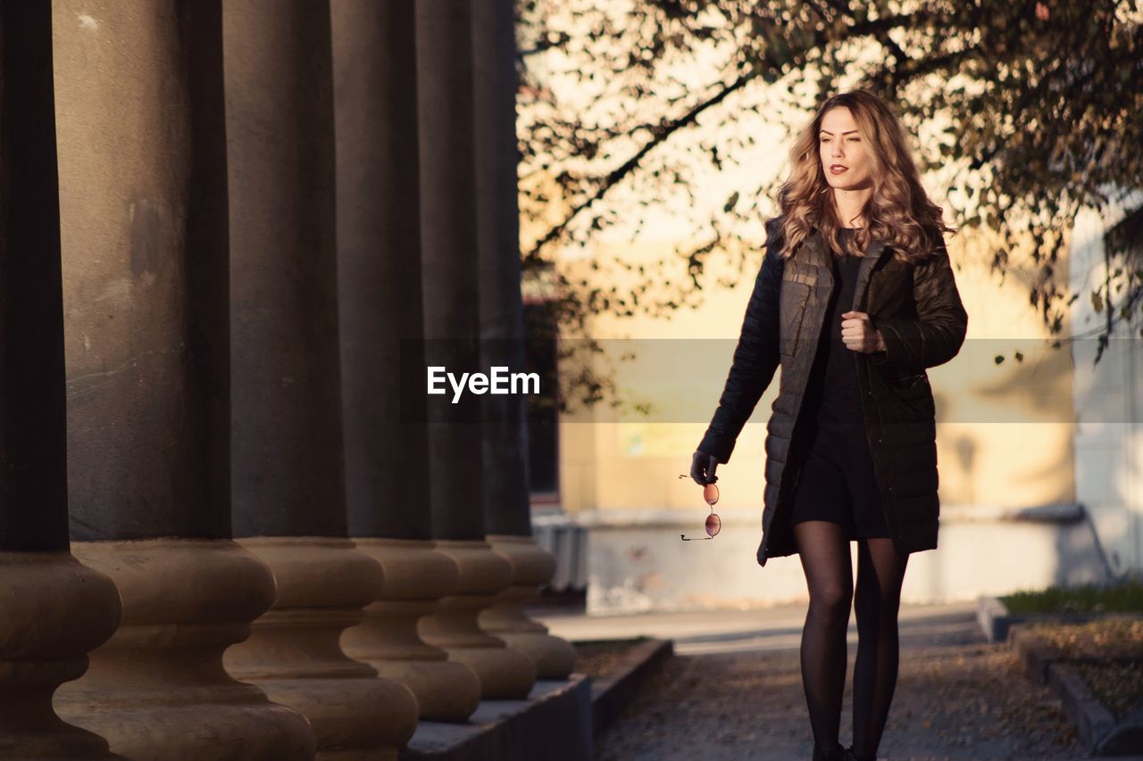 Young woman walking by columns