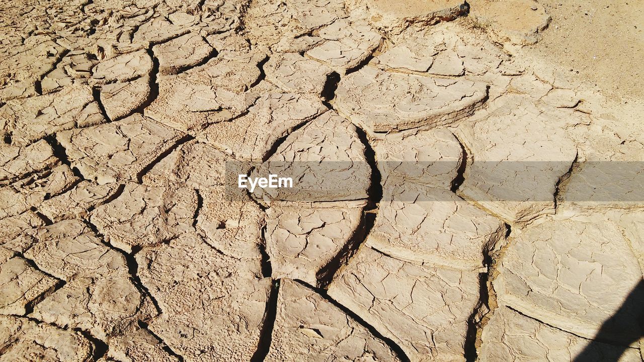 High angle view of cracked field on sunny day