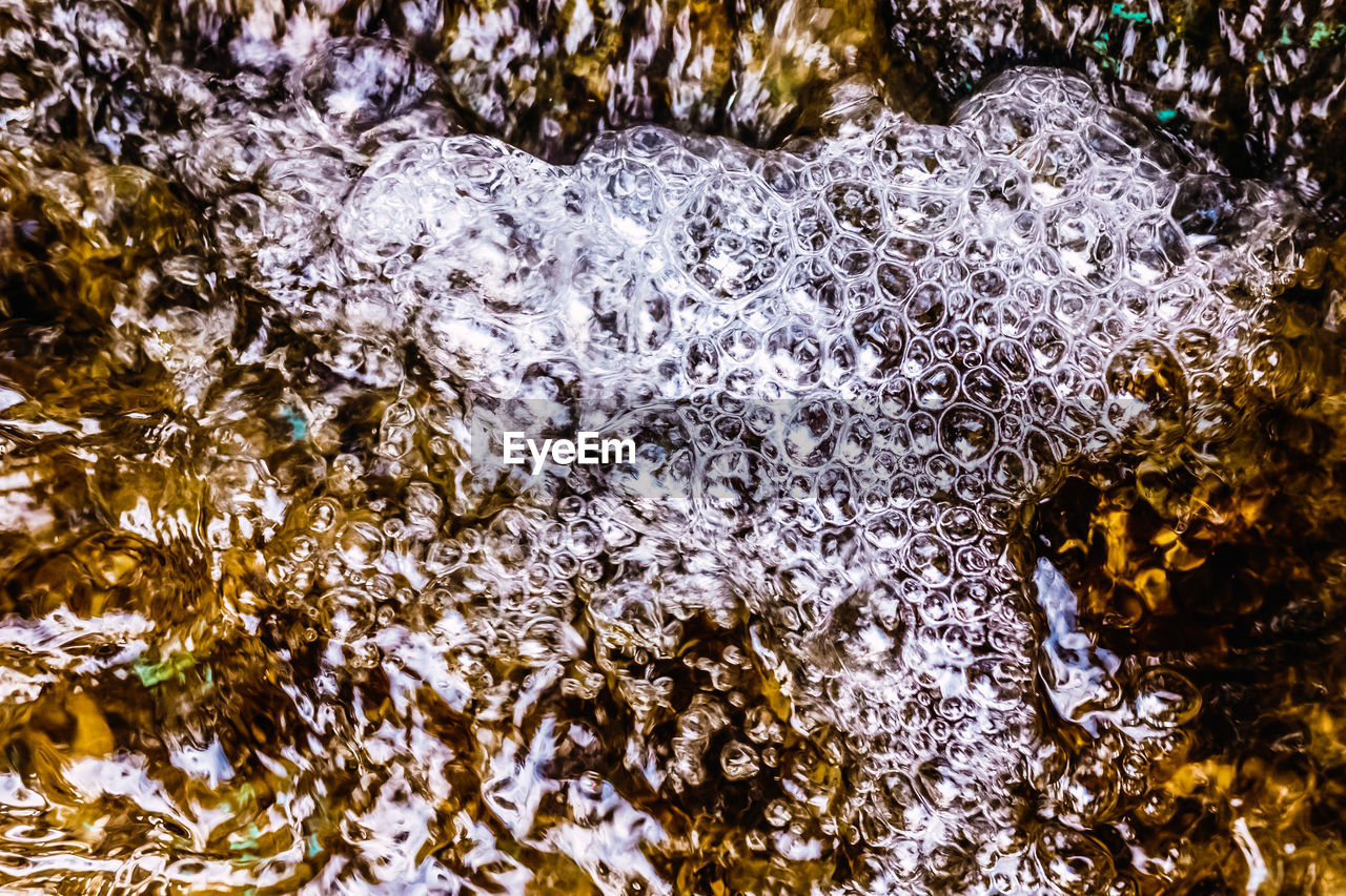 CLOSE-UP OF WATER FLOWING OVER ROCKS