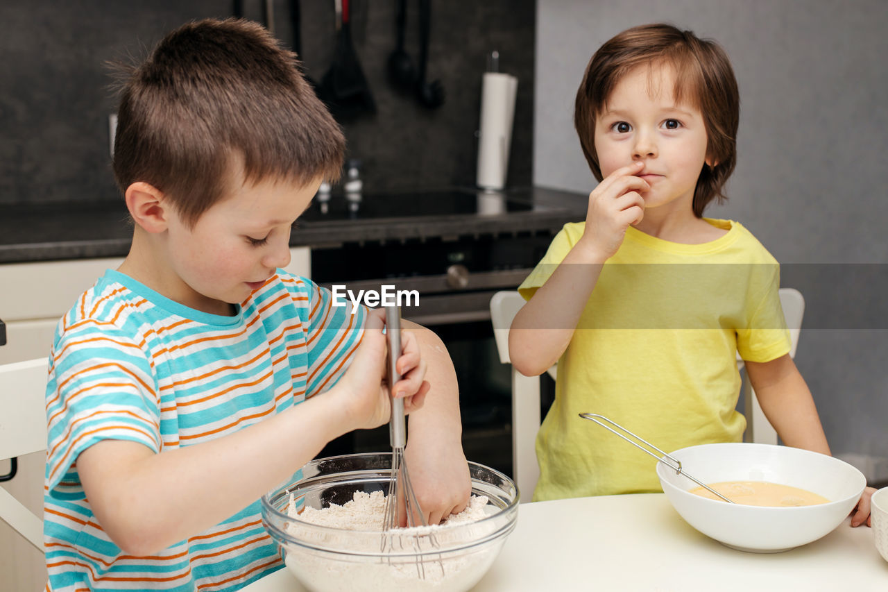 Two brothers prepare cake dough in the kitchen at home. time with children at home. 