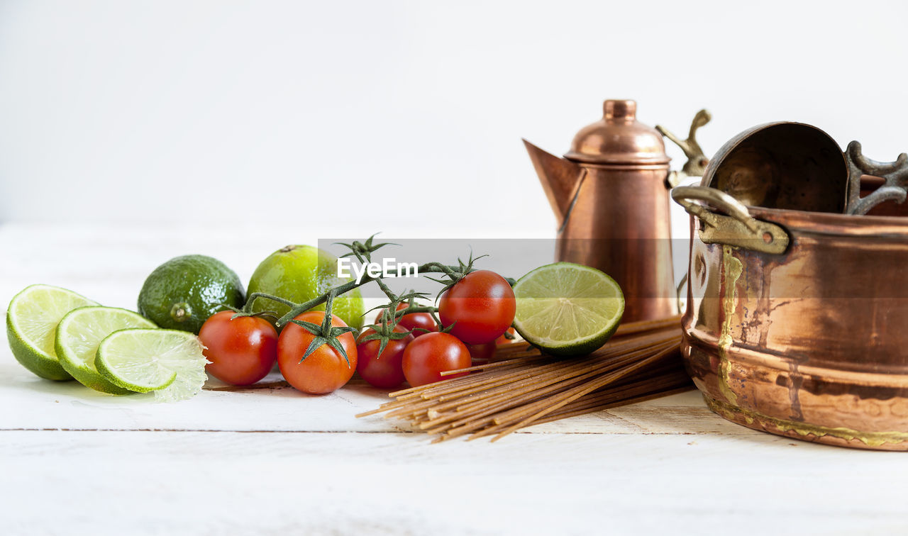 Composition of fresh vegetables pans and cutlery on white background