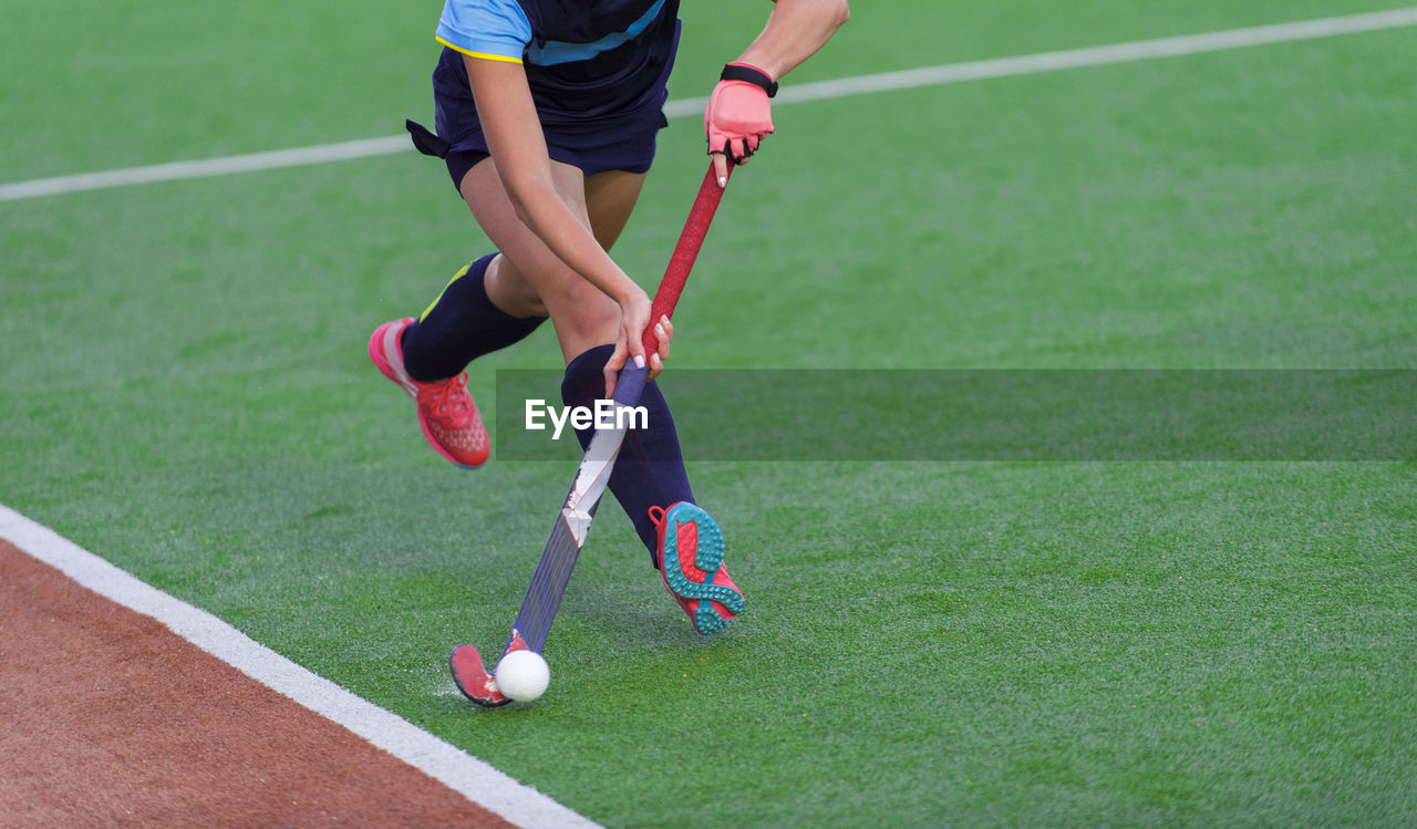 Low section of woman playing hockey in court