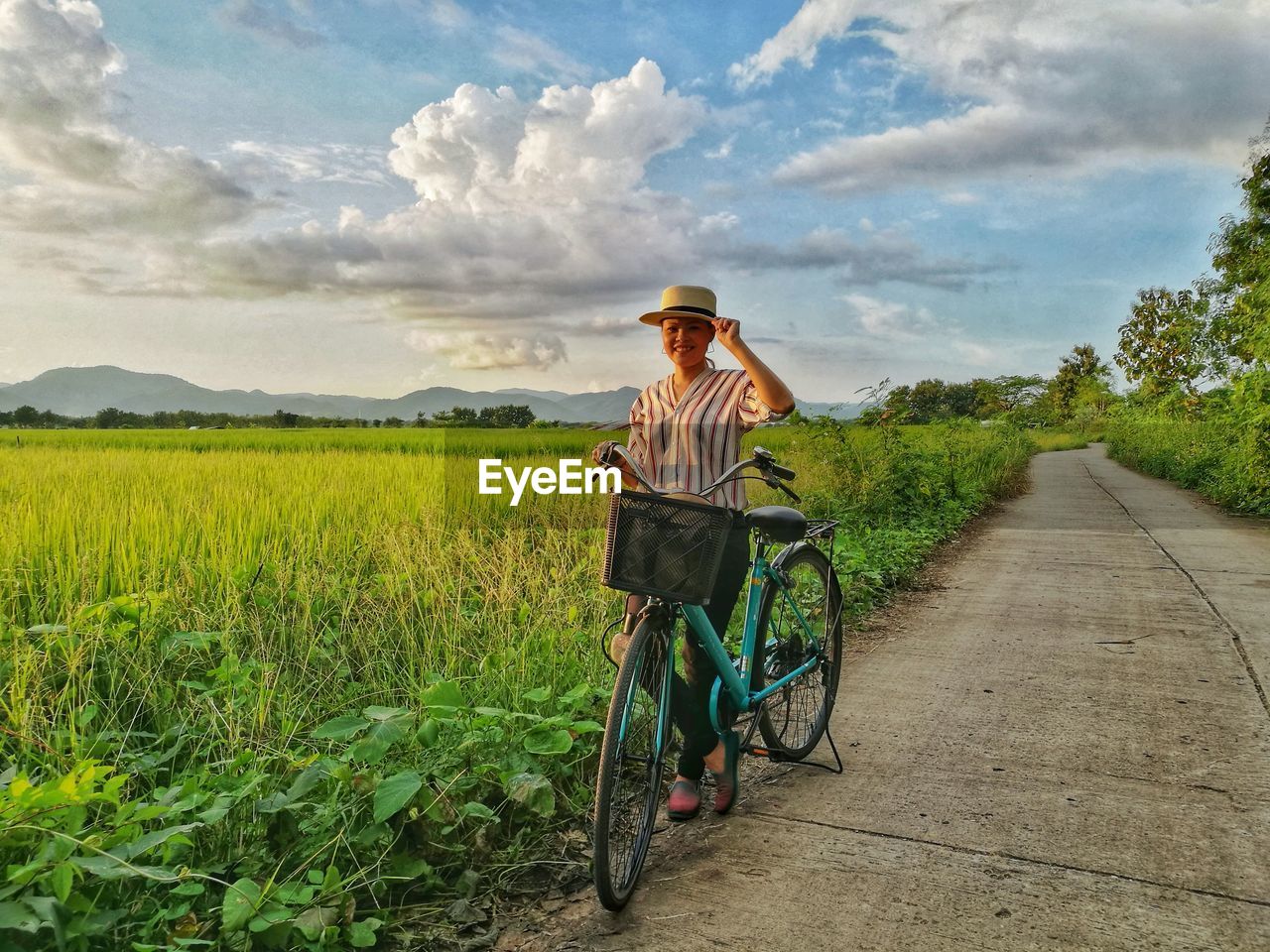 Woman standing by bicycle against agricultural field