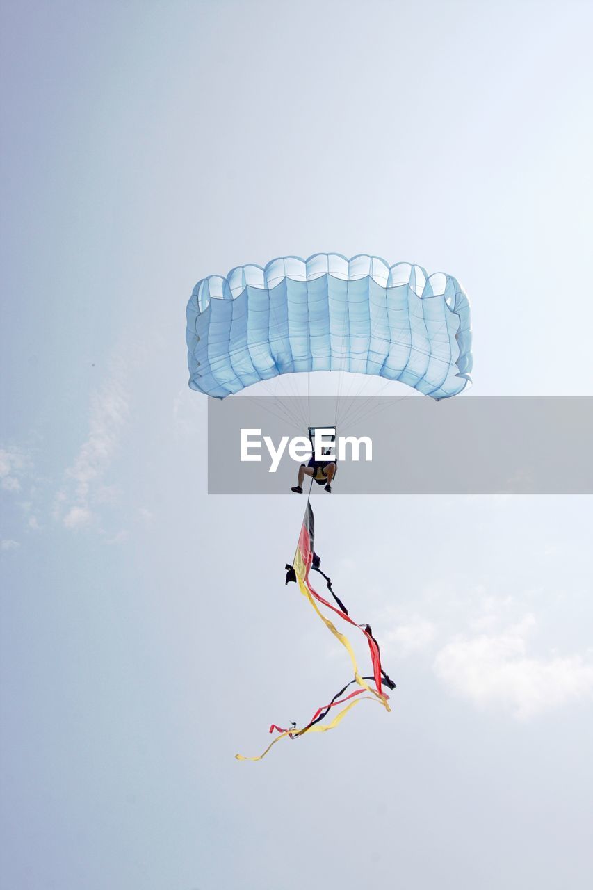 Low angle view of man paragliding against sky