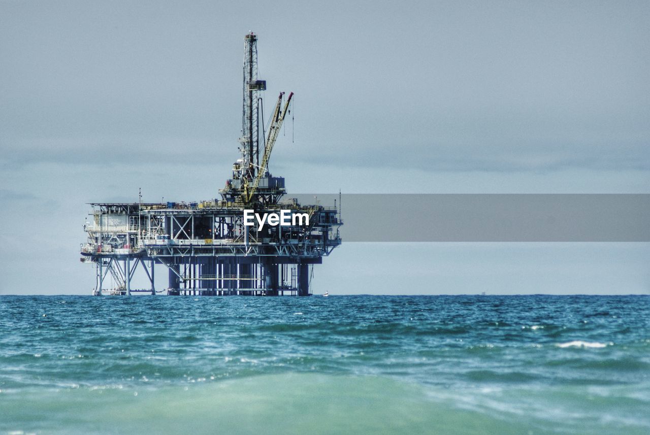 Oil rig in sea against sky