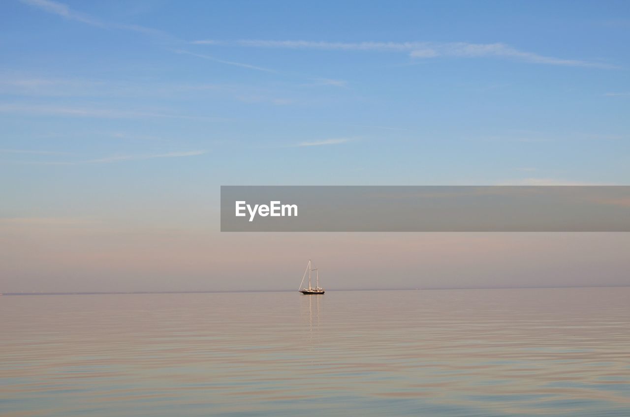 Sailboat sailing on sea against sky during sunset