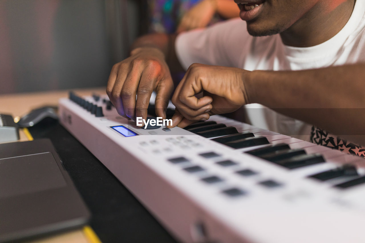 Side view of young african american partners using netbook with sound recording software on screen in music studio