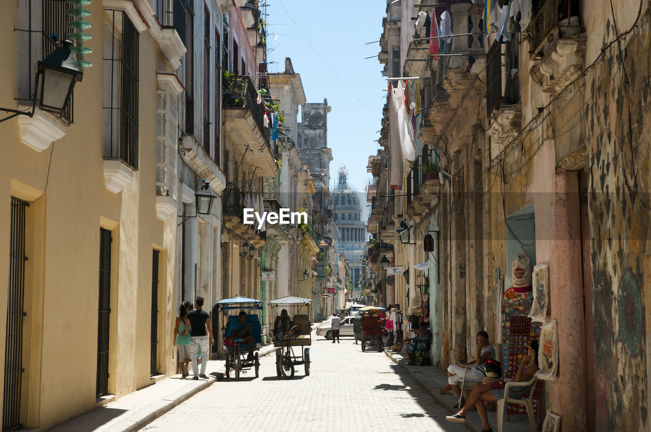 People on footpath amidst buildings in city