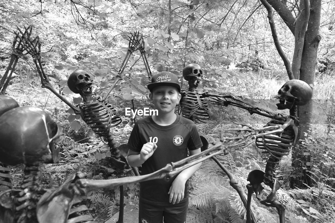 PORTRAIT OF BOYS STANDING ON TREE TRUNK