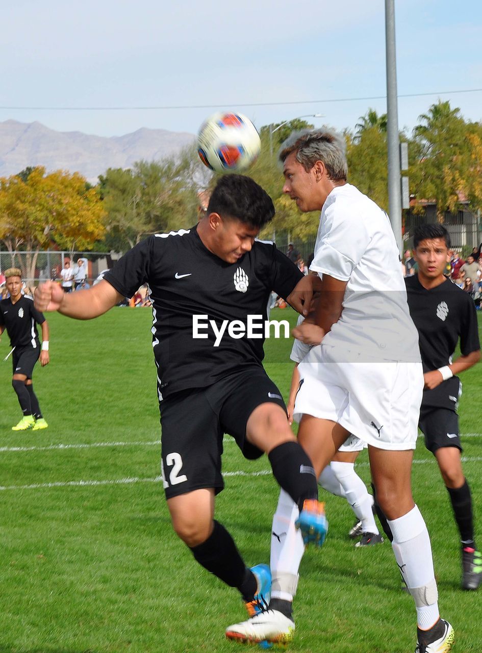 PEOPLE ON SOCCER FIELD AGAINST BRIGHT LIGHT