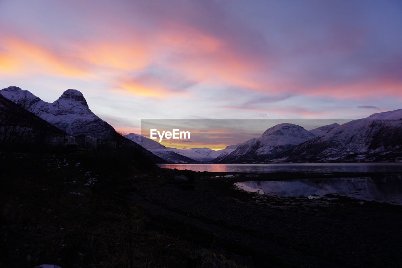 Scenic view of lake and mountains against sky during sunset