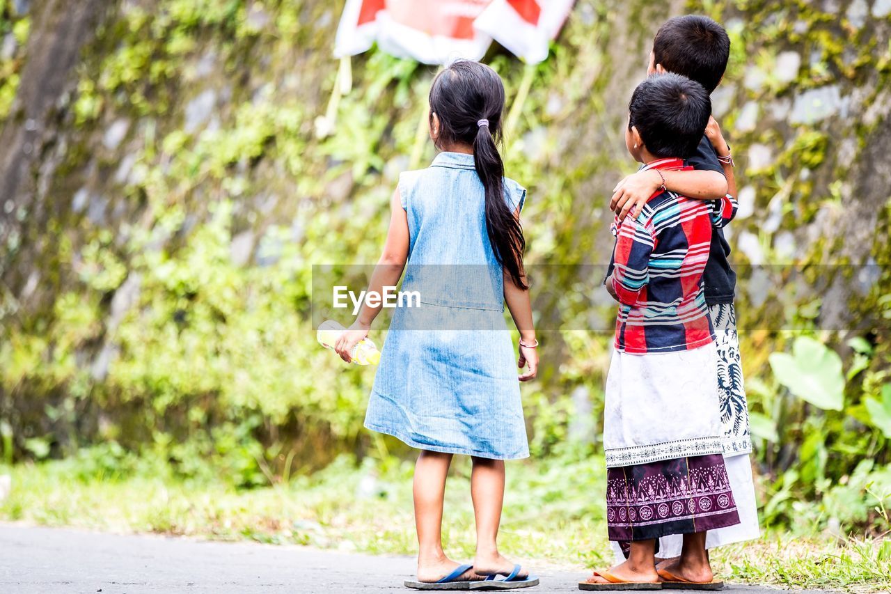 Rear view of children standing on road