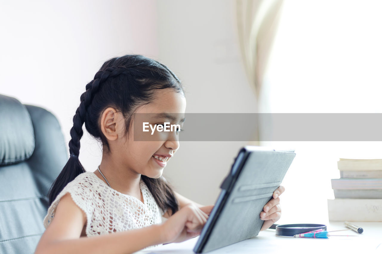 Smiling girl using digital tablet at table