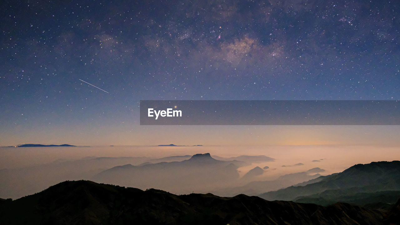 Low angle view of silhouette mountains against sky at night