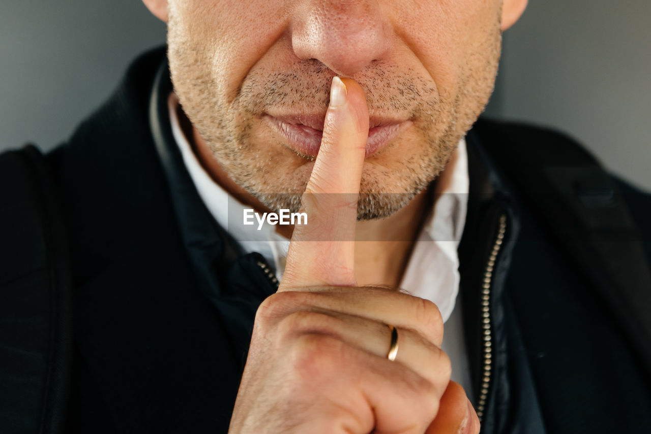 Midsection of man with finger on lips