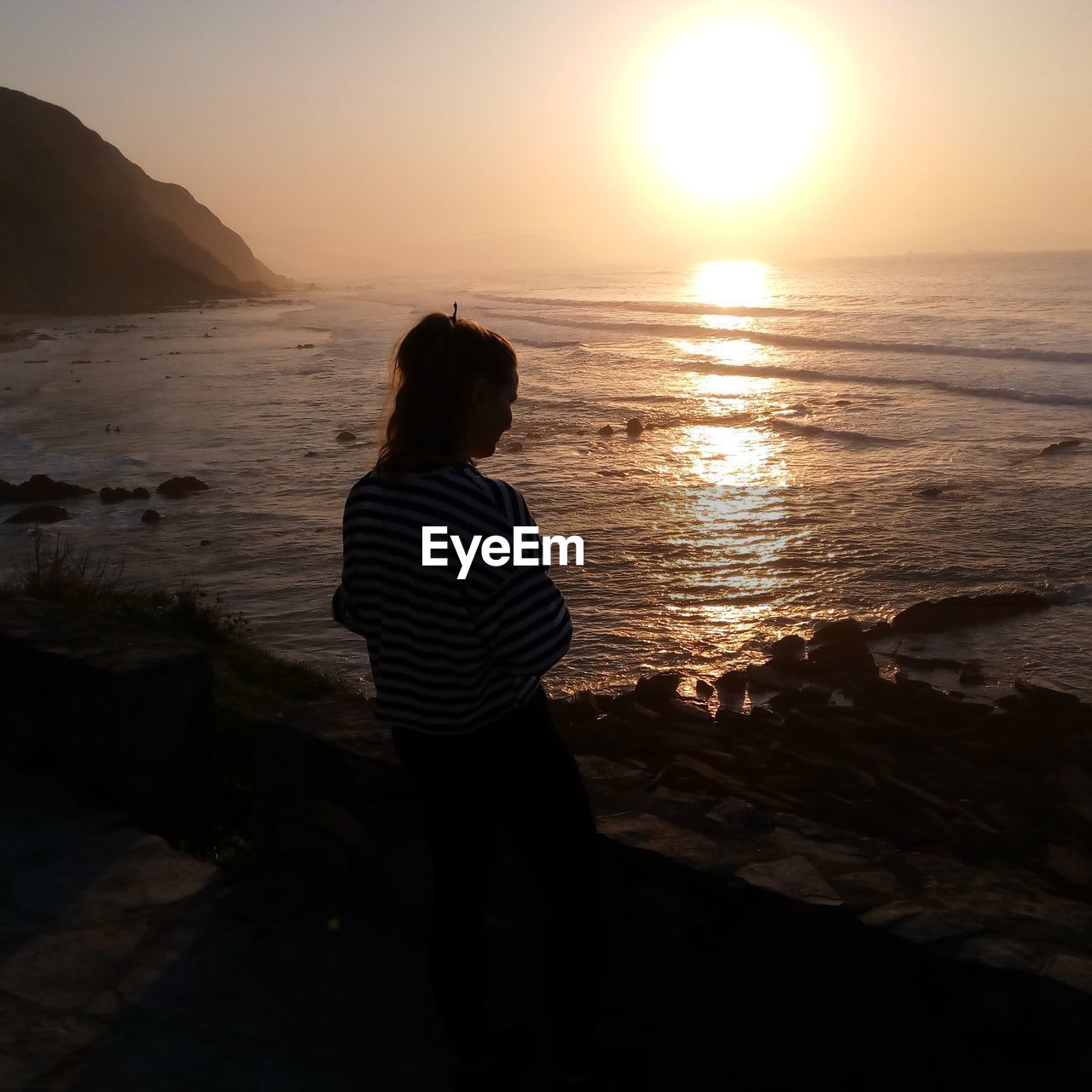 Woman standing against sea during sunset