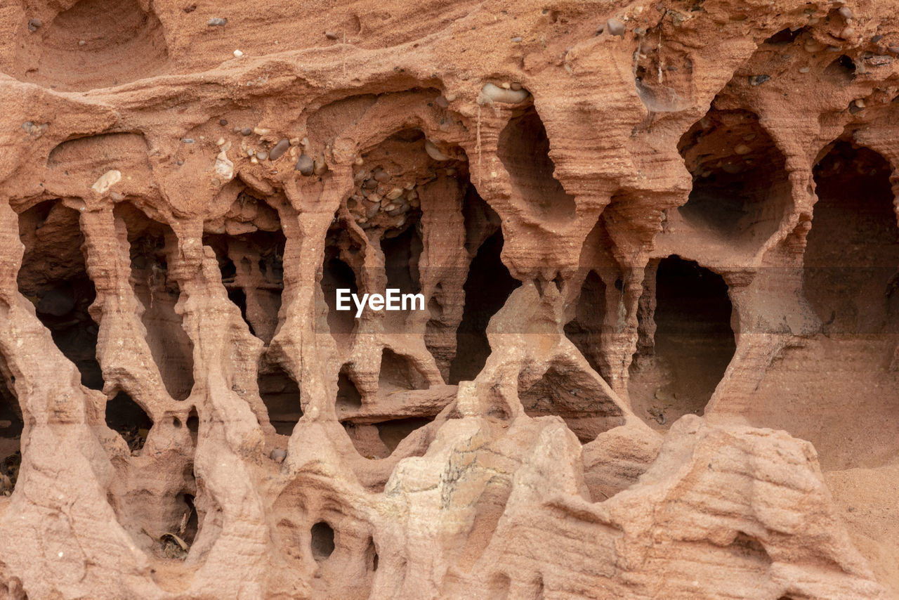 Red sandstone rocks washed out by the water with deep furrows and hollows