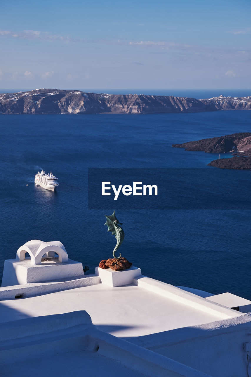 Seahorse statue in a beautiful white terrace in santorini island, greece - caldera view