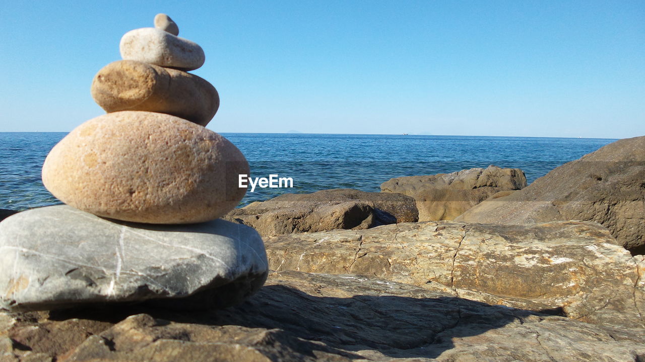 Rocks by sea against clear sky