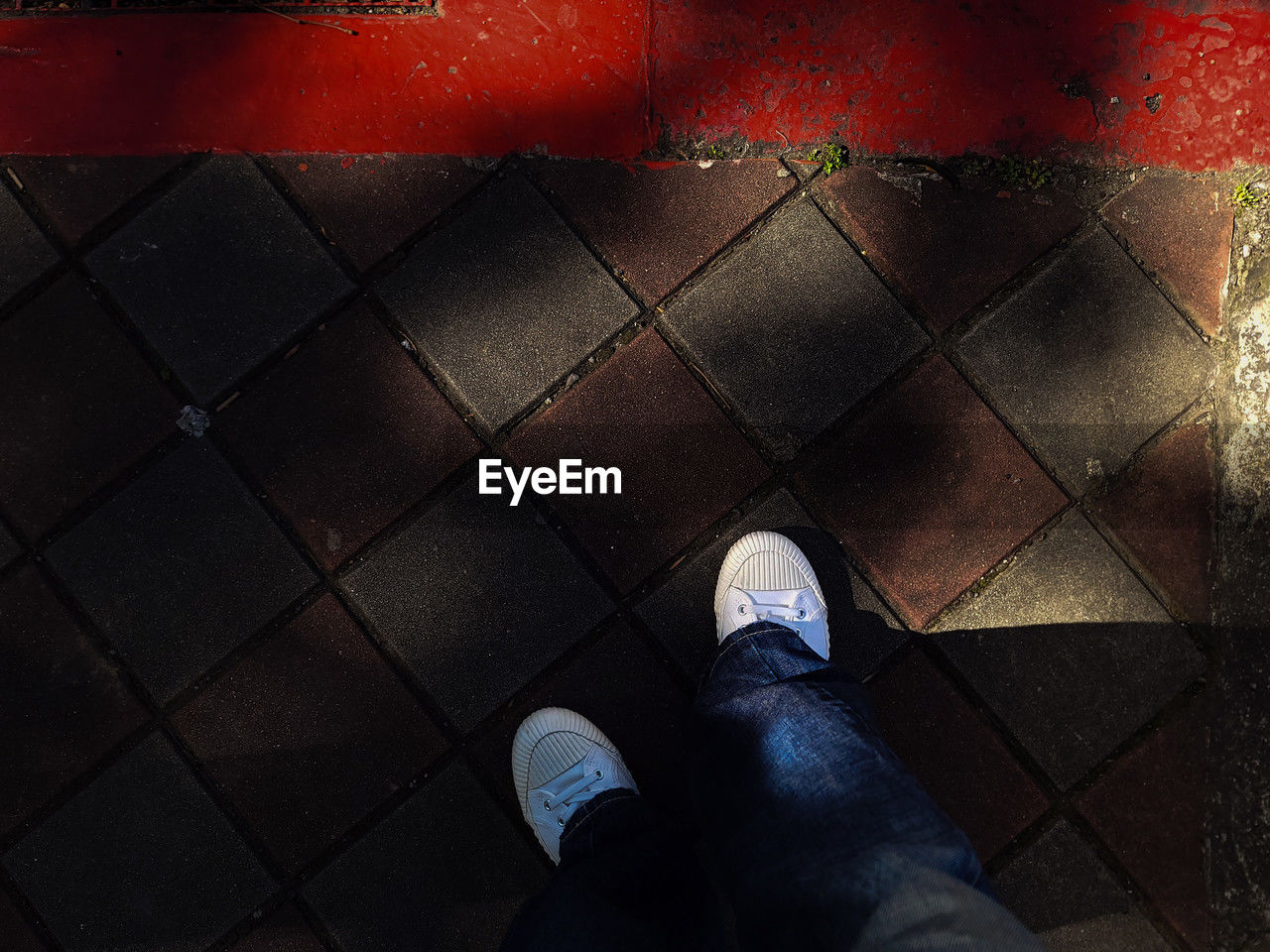 low section, human leg, shoe, red, personal perspective, light, darkness, one person, black, standing, high angle view, lifestyles, limb, human limb, men, flooring, directly above, city, human foot, footpath, blue, screenshot, leisure activity, tiled floor, jeans, shadow, casual clothing, street, adult, reflection, tile, outdoors, day, floor, footwear, clothing, wall