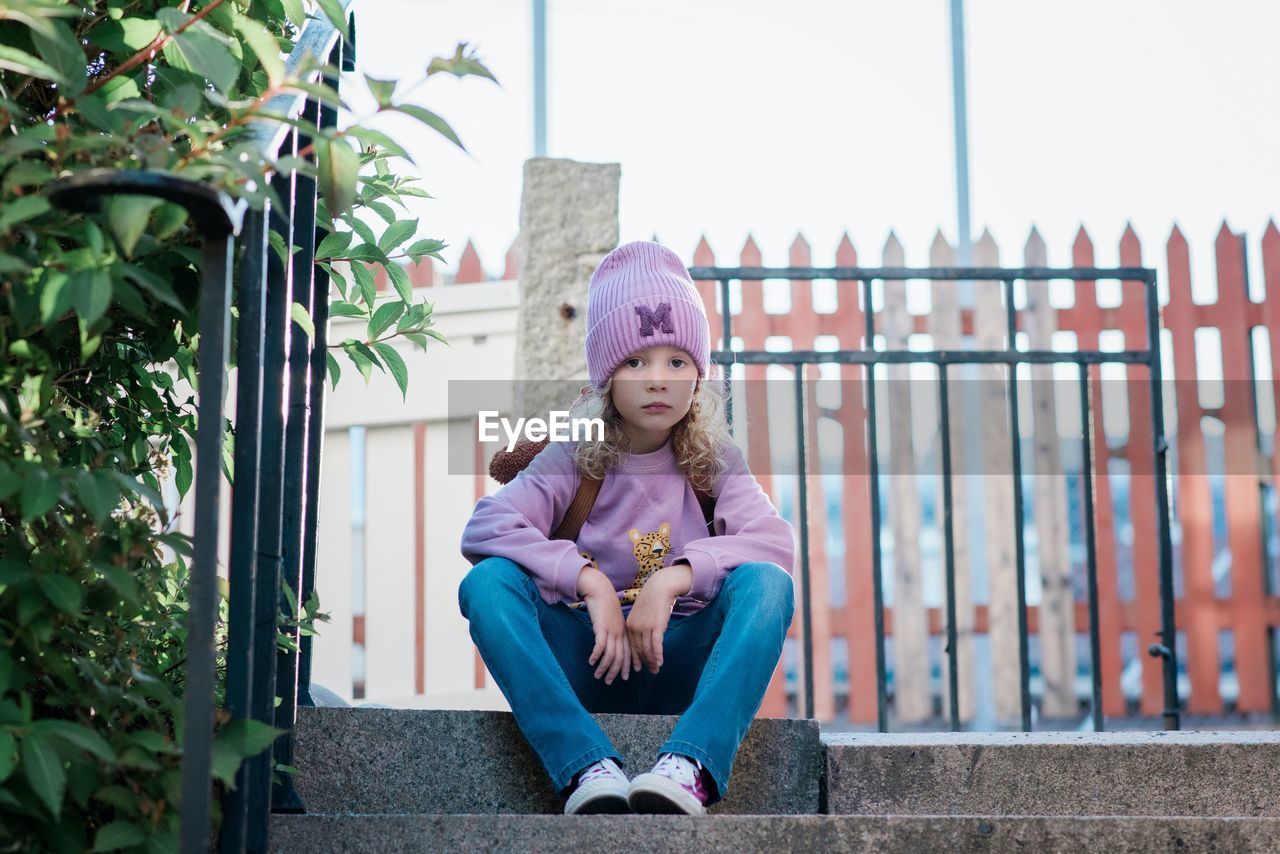 Young girl sitting on a step looking thoughtful waiting for school